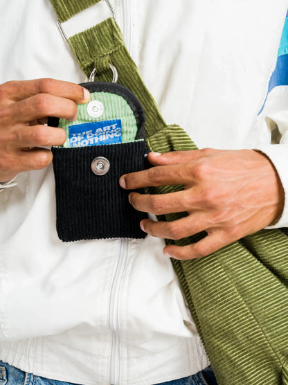 Mini black corduroy earpod pouch clipped to a green bag strap